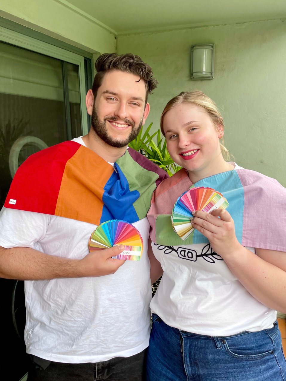 A man and woman are smiling. They are draped in their best colours and are holding their colour swatches. This couple has just enjoyed a colour analysis session together.
